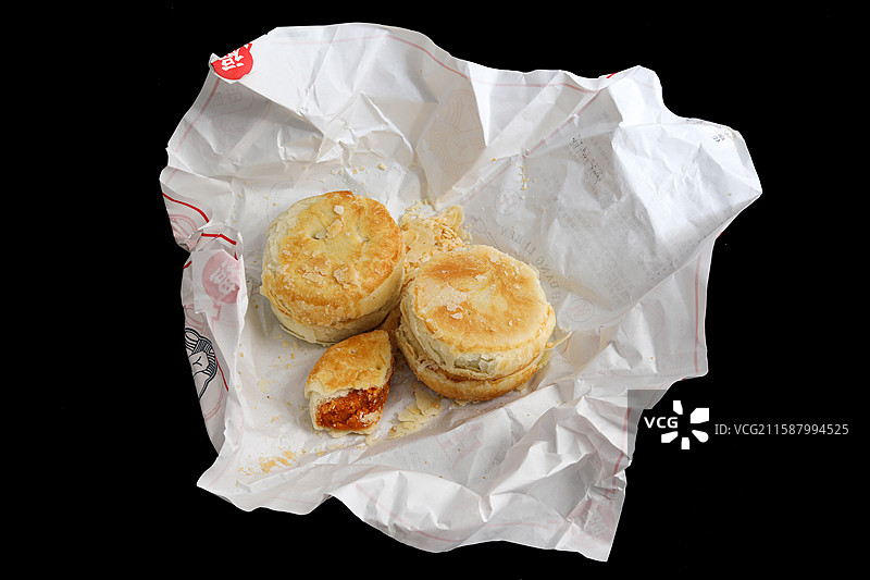 黑色背景上油纸包裹着的中国传统节日中秋节美食月饼图片素材