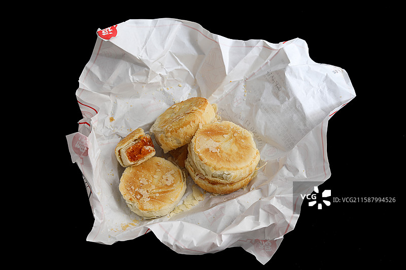 黑色背景上油纸包裹着的中国传统节日中秋节美食月饼图片素材