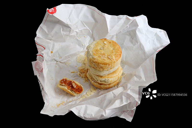 黑色背景上油纸包裹着的中国传统节日中秋节美食月饼图片素材