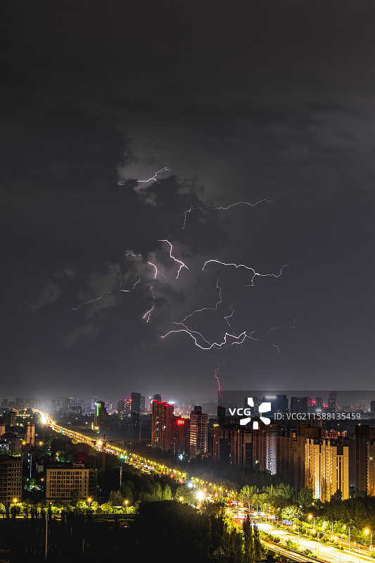 闪电炸裂宁夏银川市的夜空，楼宇剪影沉入靛蓝。雨帘斜织，雷暴如神祇怒吼，一瞬银光将城市定格为苍白的浮雕图片素材