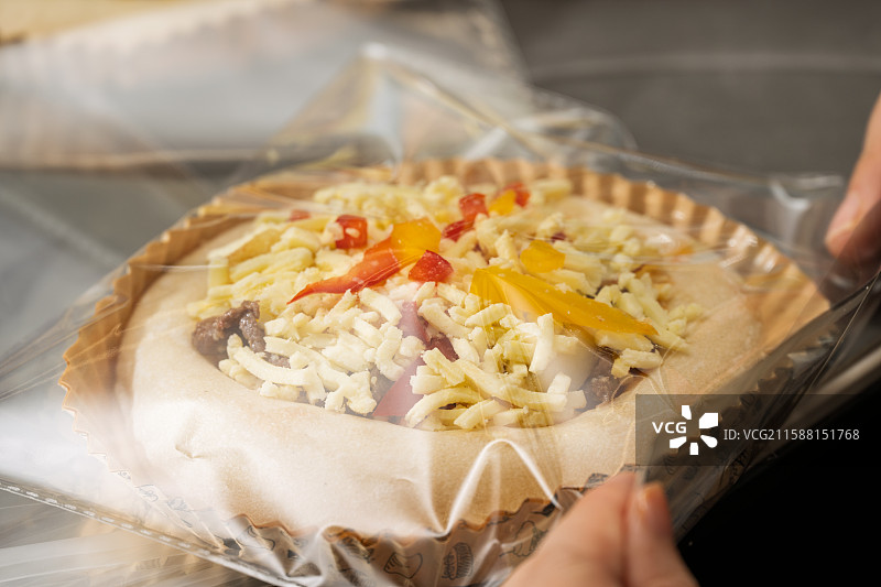 正在准备的披萨上面铺有奶酪、彩椒和香肠图片素材