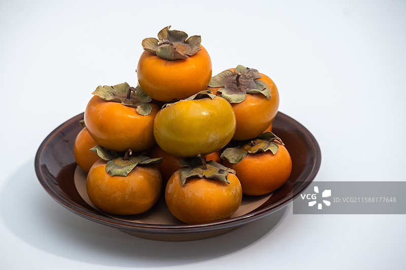白色背景上摆放着秋季新鲜采摘的柿子水果美食景观图片素材