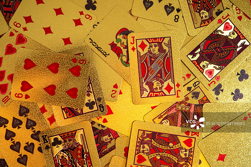 散落在桌子上的金色质感扑克牌，体现出游戏、赌博或桌面竞技概念主题图片素材