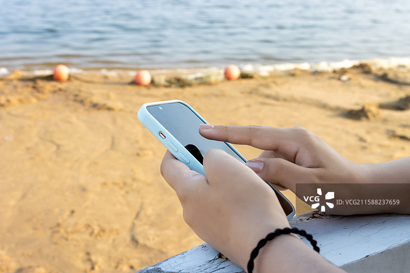 海边手持手机的手部特写图片素材