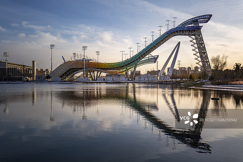 夕阳中的北京冬奥会首钢滑雪大跳台倒影在群名湖中图片素材