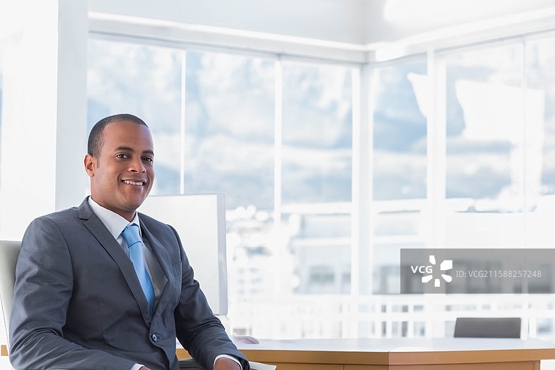 身穿西装和领带的非裔美国男性坐在办公室桌前审阅文件，留有空白空间图片素材