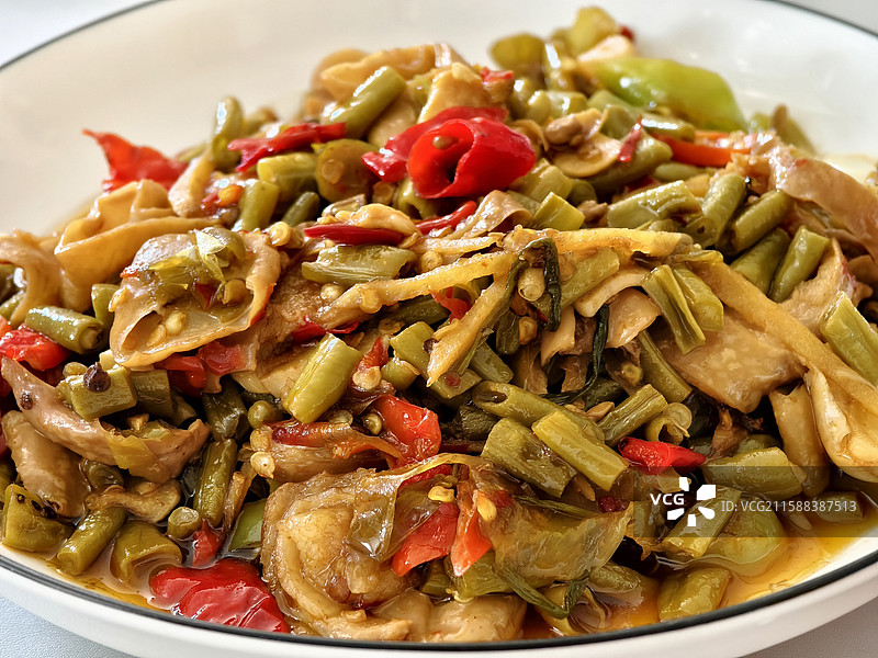 纯色背景，白色黑边的盘子装着一盘酸辣肥肠摆在桌子中间图片素材