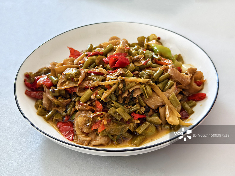 纯色背景，白色黑边的盘子装着一盘酸辣肥肠摆在桌子中间图片素材