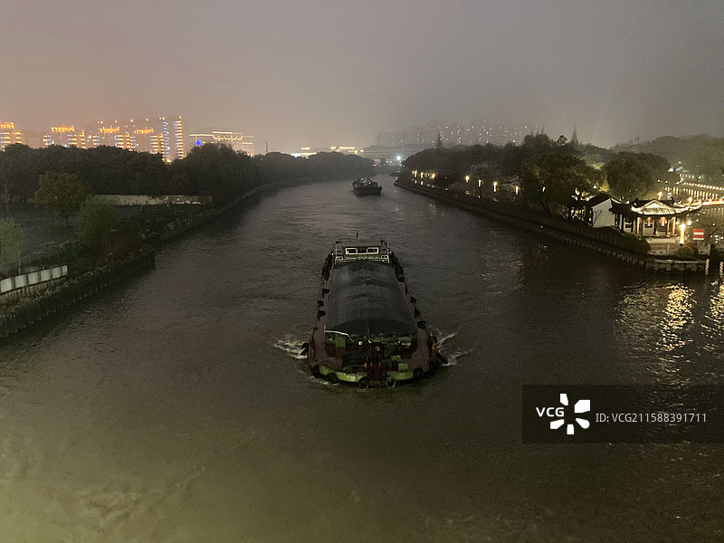 夜晚苏州城市映照下的京杭大运河和货船图片素材