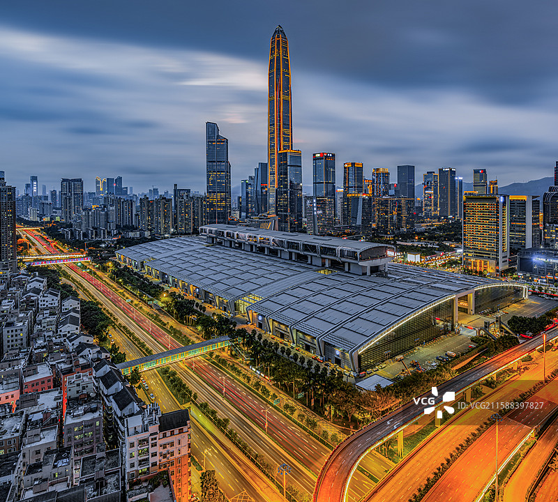 晚霞中的深圳福田区CBD城市建筑群，川流不息的十字路口旁的深圳会展中心灯火通明，平安金融中心直抵天际图片素材