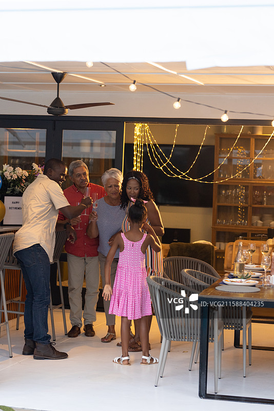 家庭在户外庆祝生日，穿着粉色裙子的非裔美国女孩微笑着图片素材