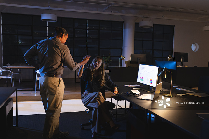 同事们在夜间办公室讨论项目，分析电脑屏幕上的数据图片素材