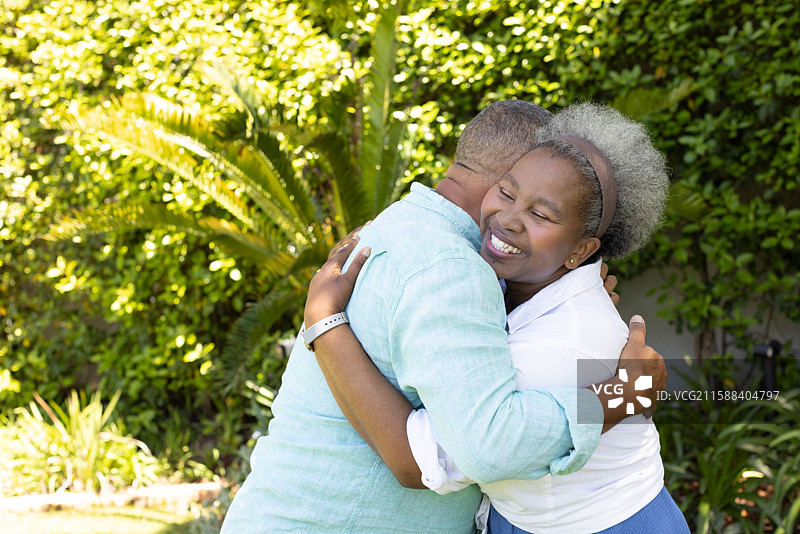 非裔美国老年夫妇在郁郁葱葱的花园中快乐地相拥图片素材