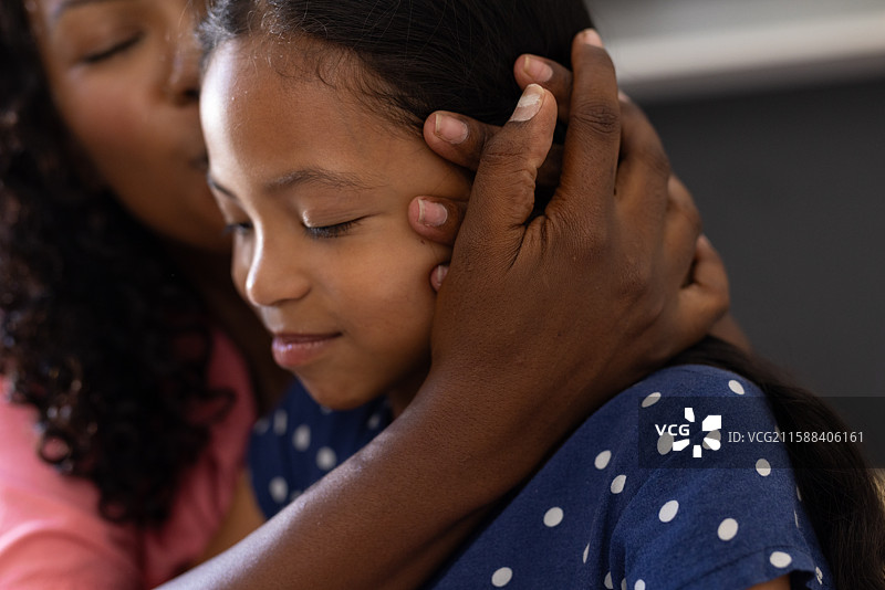 非洲裔美国母亲亲吻女儿的额头，表达爱与关怀图片素材