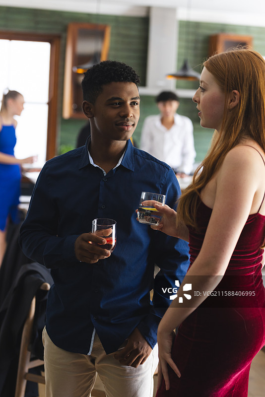 青少年在热闹的学校聚会上喝饮料聊天图片素材
