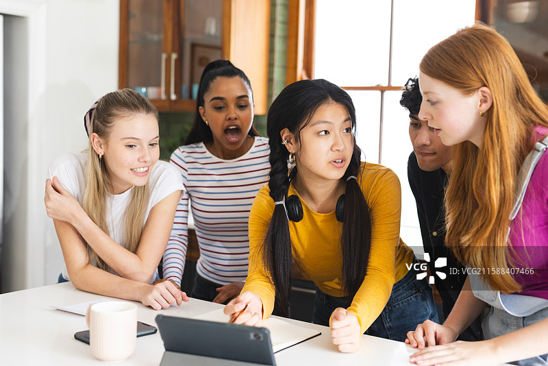 青少年在现代厨房环境中使用平板电脑合作完成学校项目图片素材