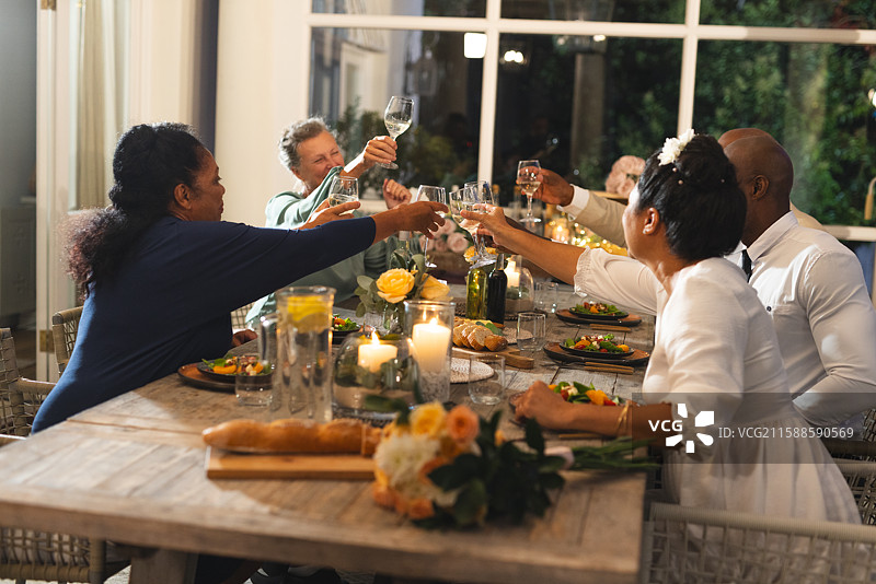 家庭在家中庆祝晚餐，举杯欢快地祝酒图片素材