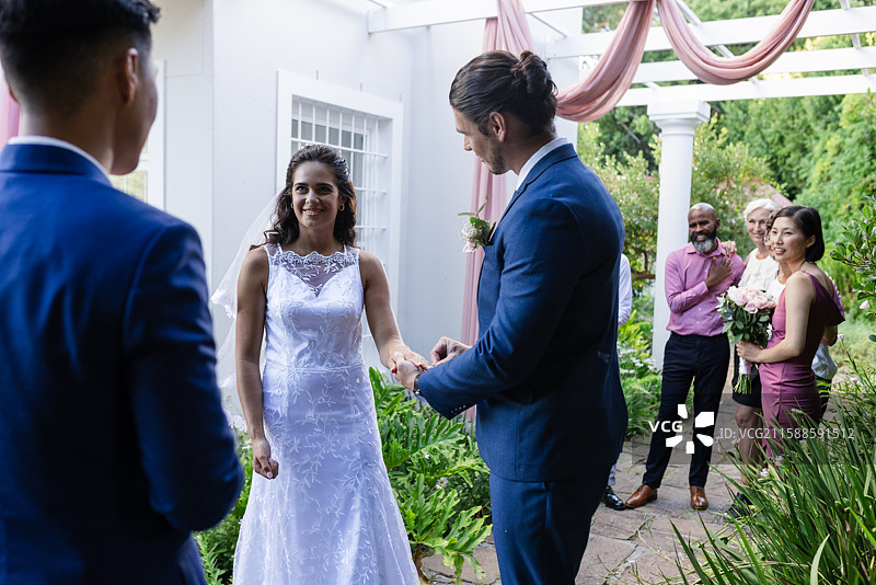 新娘和新郎在户外交换誓言，周围是快乐的朋友和家人图片素材