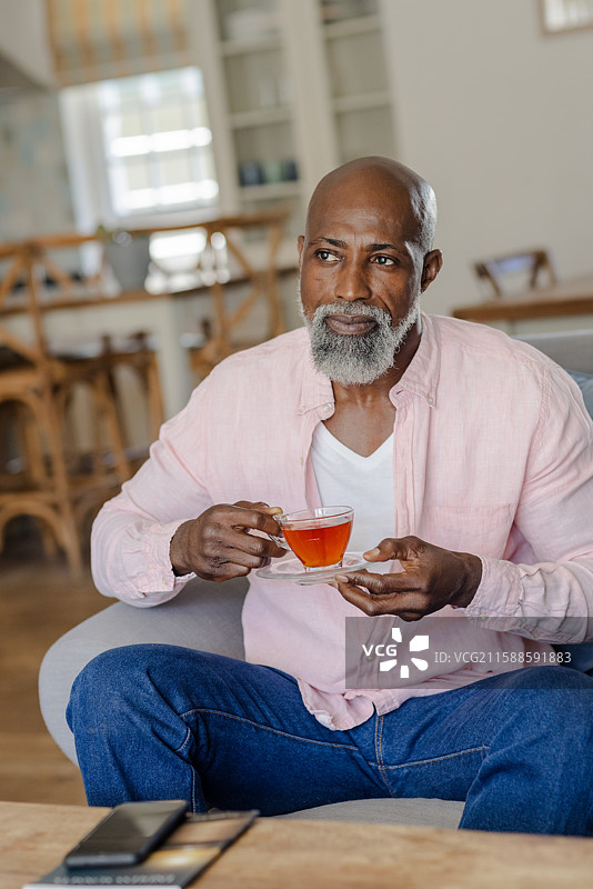 老年人在家中享受茶时光，悠闲地坐在舒适的客厅椅子上图片素材