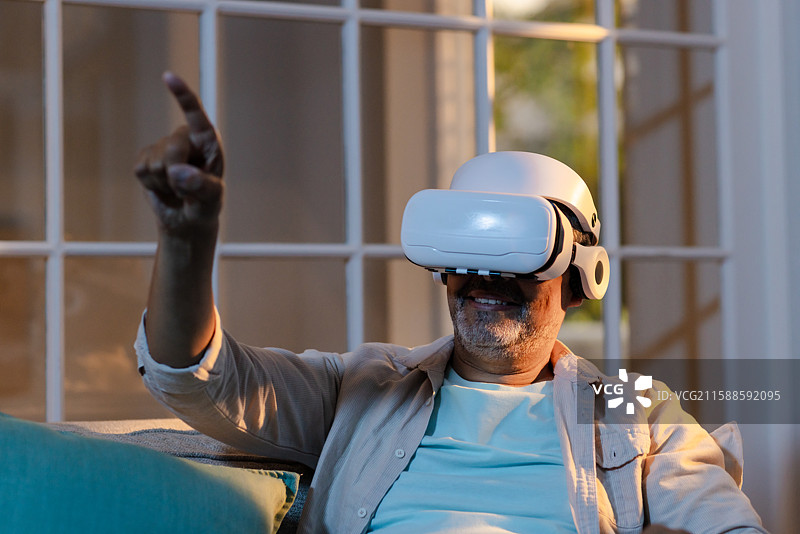 老年人在家中使用虚拟现实头盔，探索虚拟现实体验图片素材