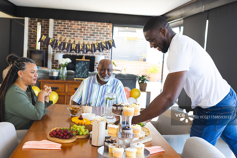庆祝退休，家人分享杯子蛋糕和水果，共同享受快乐时光图片素材