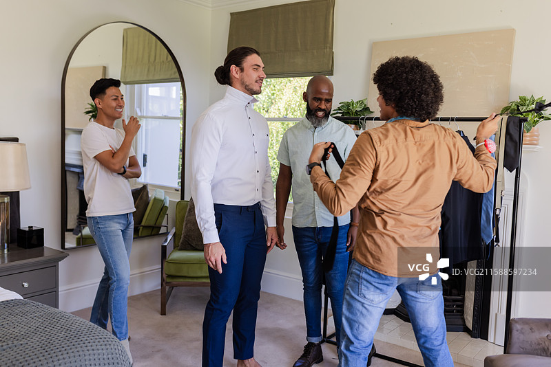 新郎与朋友们在卧室里准备，调整领带并分享欢笑图片素材
