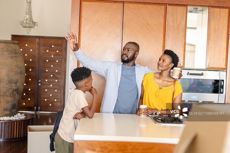 父亲兴奋地向家人讲解厨房装修计划，手里拿着咖啡。图片素材