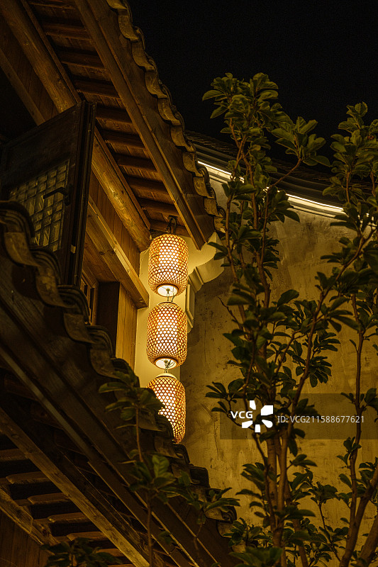 夜色中古建筑外墙悬挂的灯笼散发温暖光辉图片素材
