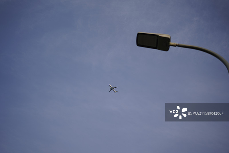 路灯和飞机迎天飞行的低角度视图图片素材