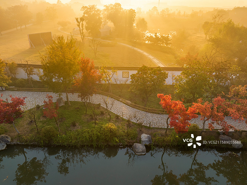 苏州天平山秋日公园，小路旁红叶黄叶相映，水域倒映美景，晨光照亮金黄天空，宁静美丽。图片素材