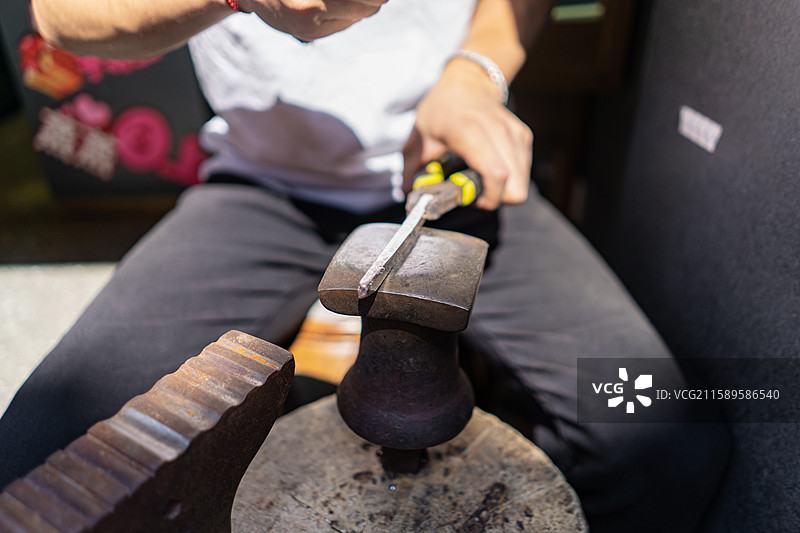 中国时尚配饰首饰拍摄主题，商店里一个工人正在用锤子砸银器制作银饰首饰饰品，室内工匠图像摄影图片素材