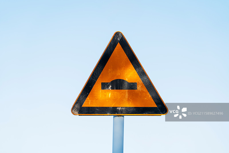 天空下三角形交通标识牌注意路面不平图片素材