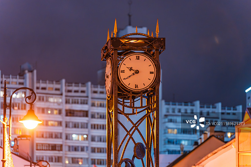 夜晚城市街头一座带有多个表盘的复古风格金属立式时钟图片素材