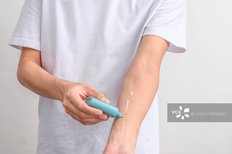 白色背景前涂美白防嗮护肤产品的人图片素材