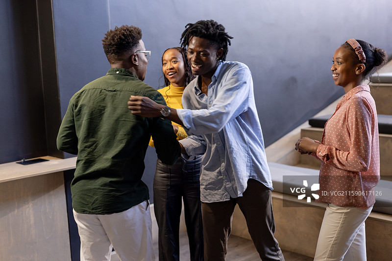 非裔美国同事在现代办公室环境中热情问候彼此图片素材