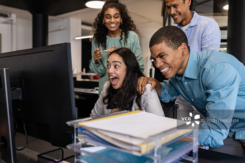 多元化的商业团队在现代办公室里庆祝成功，同时查看电脑。图片素材