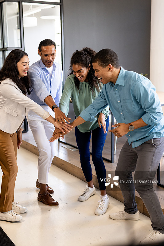 多元化的商业团队在现代办公室庆祝成功，大家一起击掌庆祝图片素材