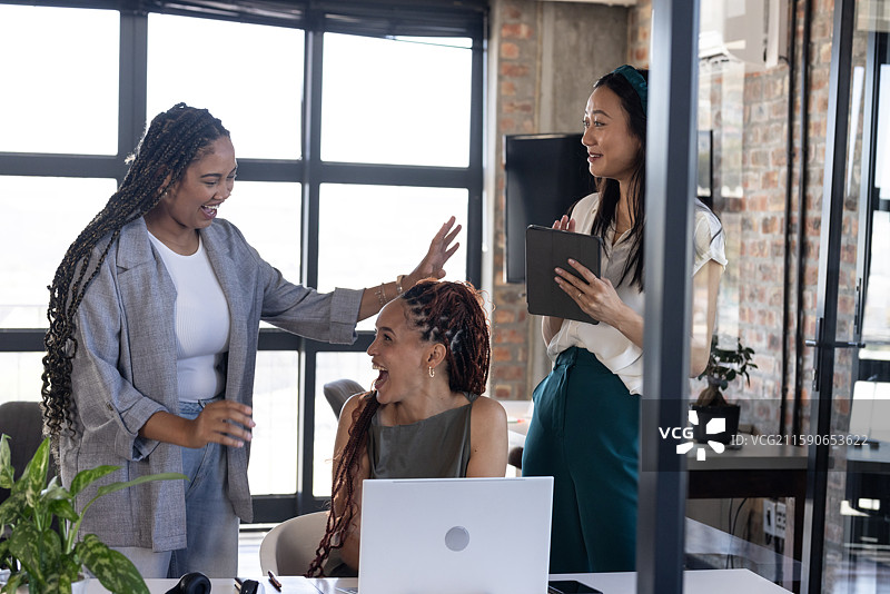 同事们在办公室庆祝成功，手里拿着笔记本电脑和数字平板。图片素材