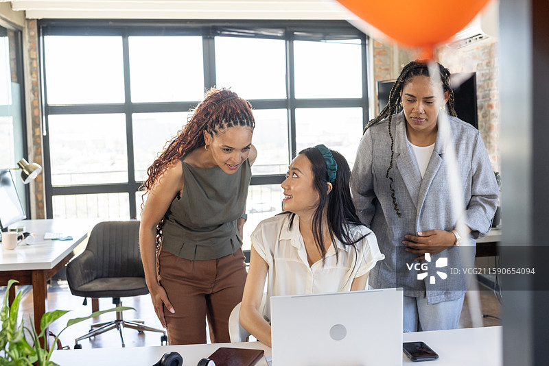 同事们在现代办公室桌前庆祝成功，微笑并讨论项目图片素材