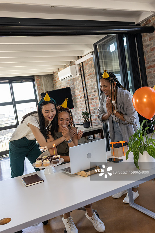 同事们在现代办公室里通过视频通话庆祝生日，享用杯子蛋糕。图片素材