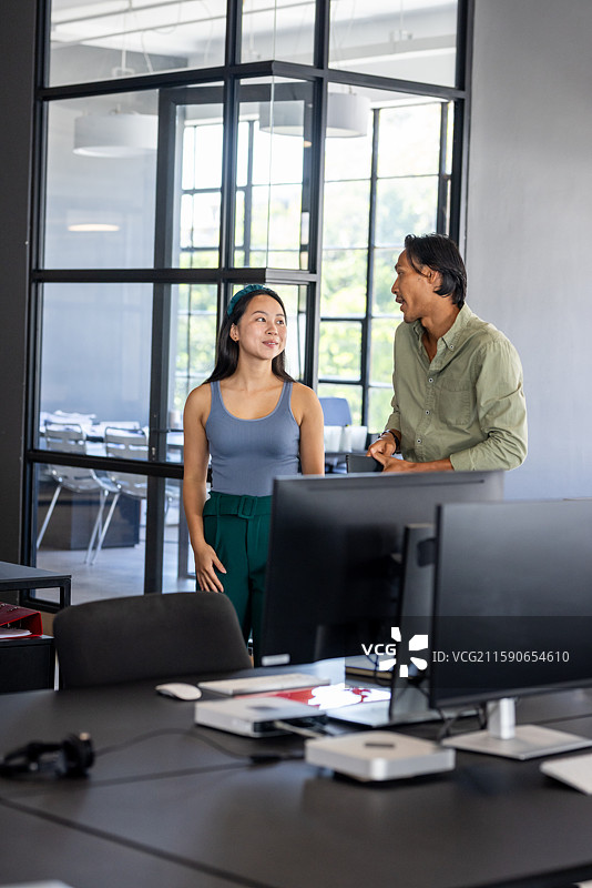 同事们在现代办公室讨论项目，站在大窗户旁边图片素材