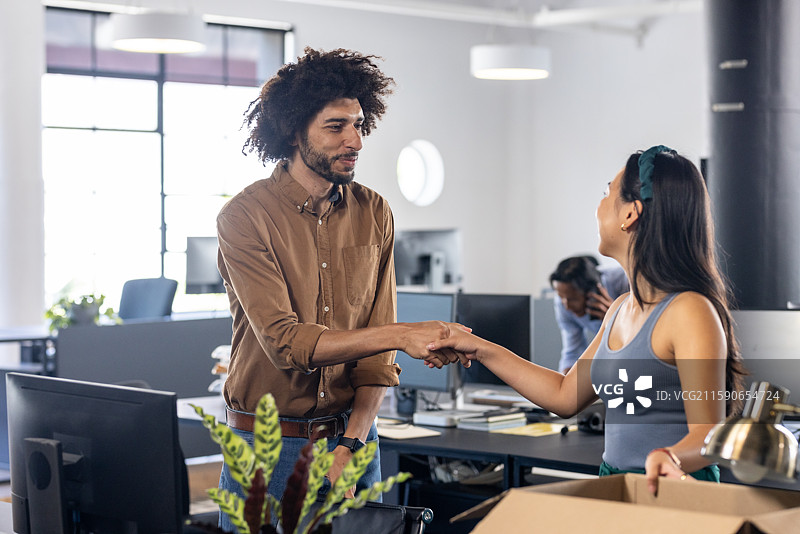 在现代办公室，同事们握手庆祝成功的工作合作图片素材