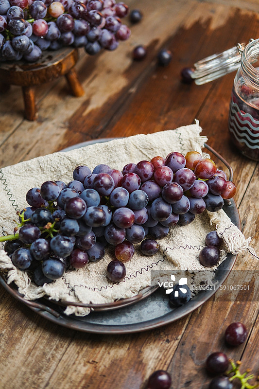 暗调静物影棚拍摄盘子里成串的水果葡萄图片素材
