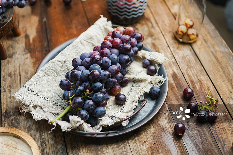 暗调静物影棚拍摄盘子里成串的水果葡萄图片素材