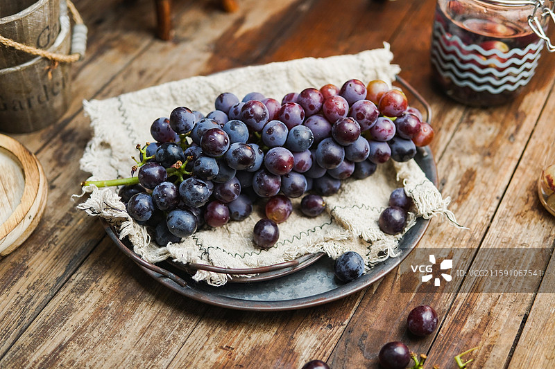 暗调静物影棚拍摄盘子里成串的水果葡萄图片素材