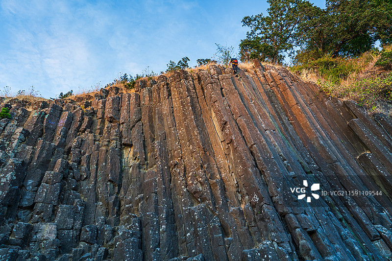 金色阳光下，攀岩者在俄勒冈州尤金市的柱状玄武岩岩壁上攀爬图片素材
