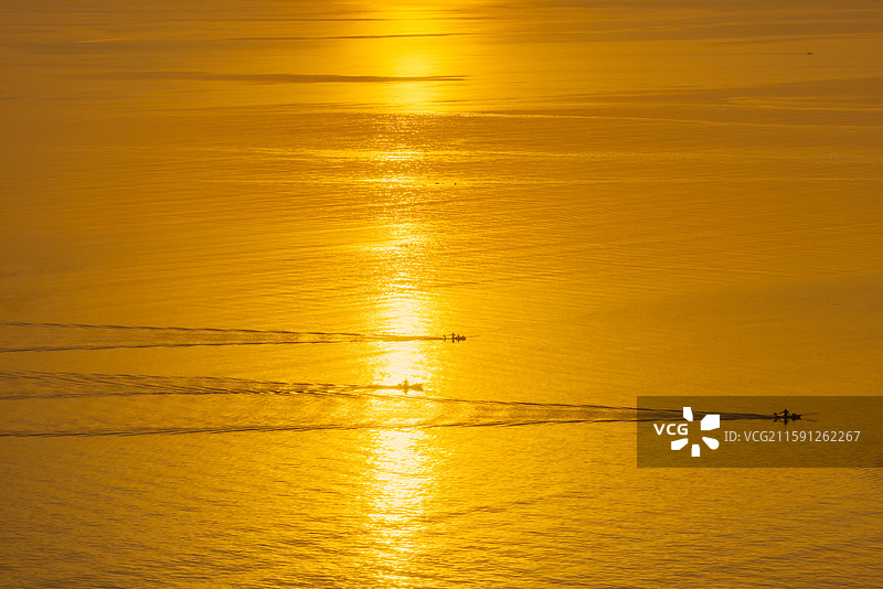 日出时分的烟台金沙滩景区海面上的讨海人图片素材