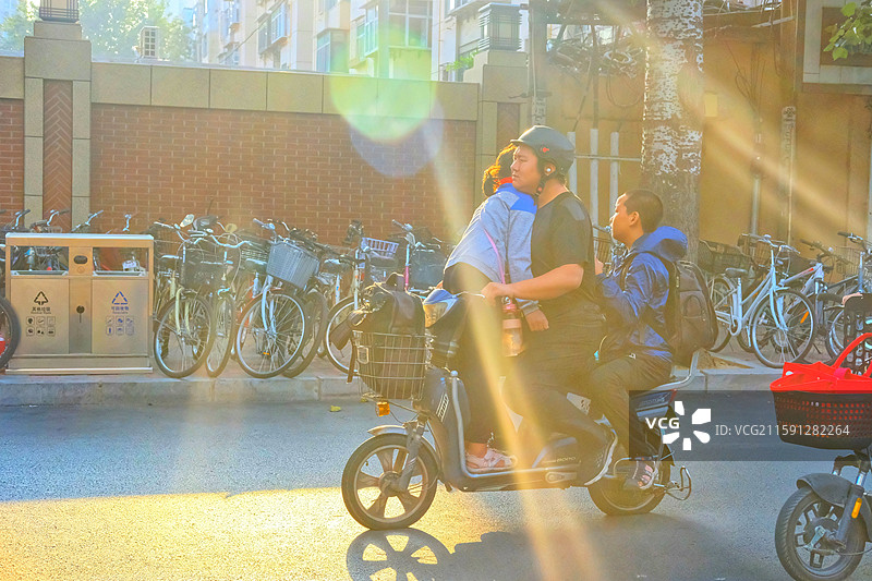 清晨明媚阳光中，送孩子们上学的家长们。城市生活。红领巾学生光影图片素材