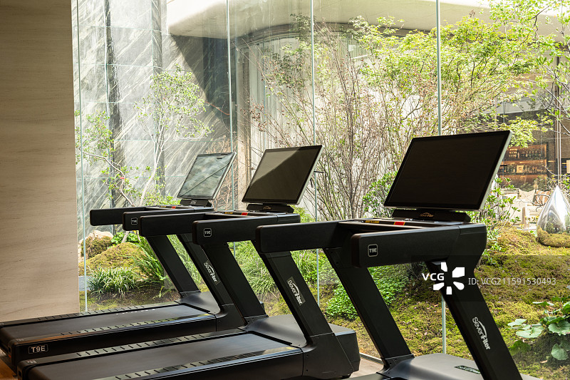靠窗摆放的跑步机与绿色景观图片素材