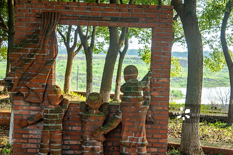 祝甸村内，砖制雕塑展现勇气与合作，背景自然环绕。图片素材